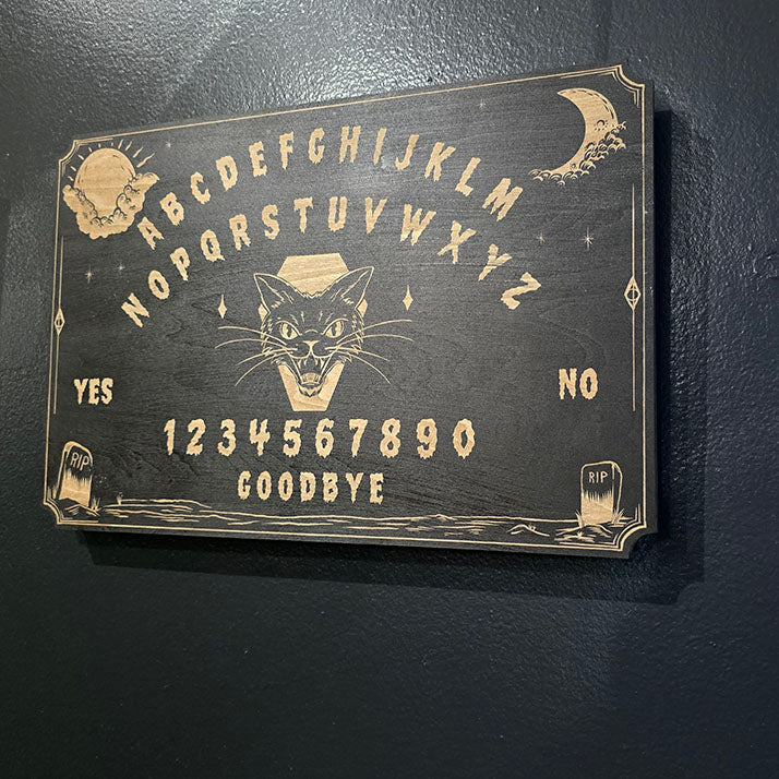 Ouija board with a black cat illustration on a dark background