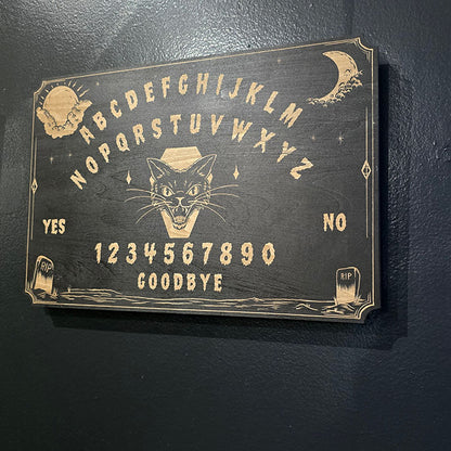 Ouija board with a black cat illustration on a dark background
