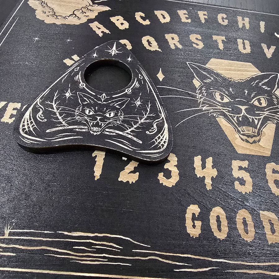 Ouija board with a black cat illustration on a dark background